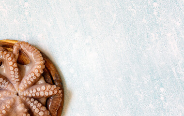 Large octopus tentacles on a wooden Board for Stripping on a blue background. Octopus on the kitchen table. Preparing to cook octopus