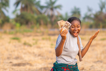 female african farmer feeling excited and happy holding money in her hand