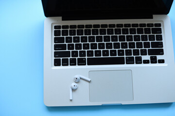 Mockup . The laptop and air pods on keyboard .blue background