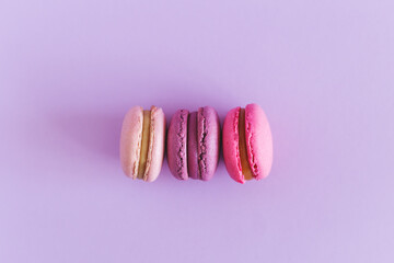 Tasty french macarons on a violet pastel background. Pink and violet macarons.