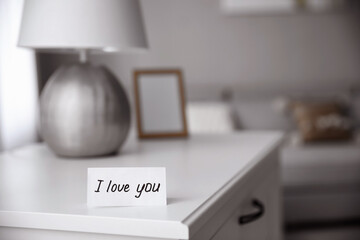 Paper with text I Love You on nightstand indoors