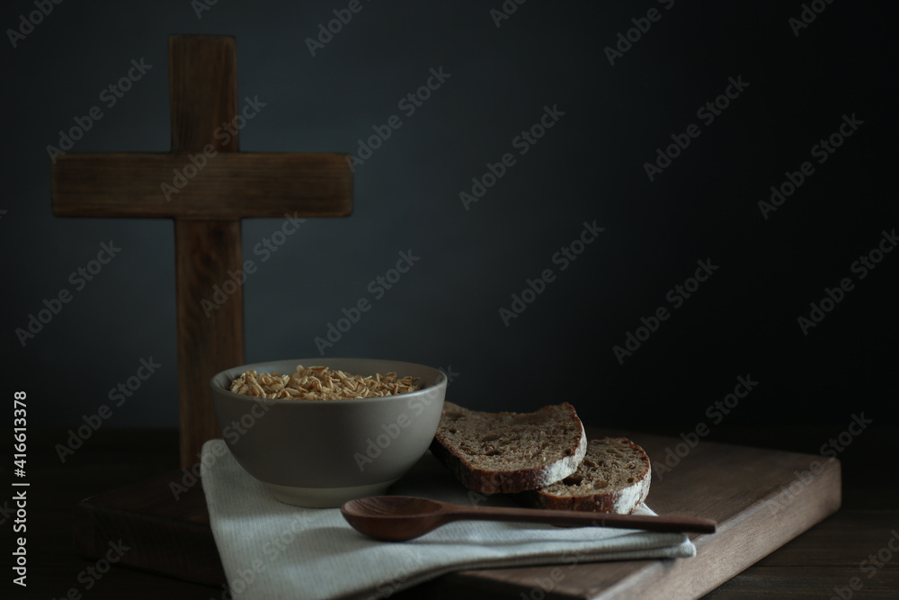 Wall mural oatmeal porridge, bread and cross on wooden table, space for text. lent season