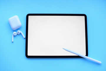 Mockup . Tablet with Pencil and air pods on blue background
