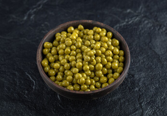 Close up photo of Bowl full with Green marinated olives on black background