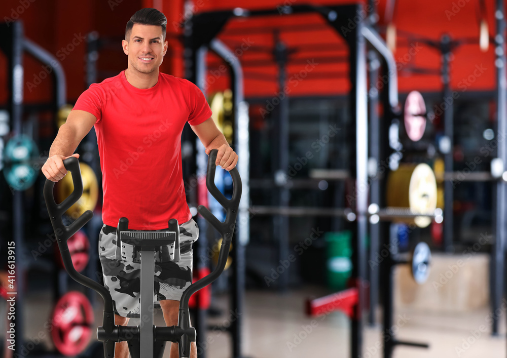 Canvas Prints Man using modern elliptical machine in gym, space for text