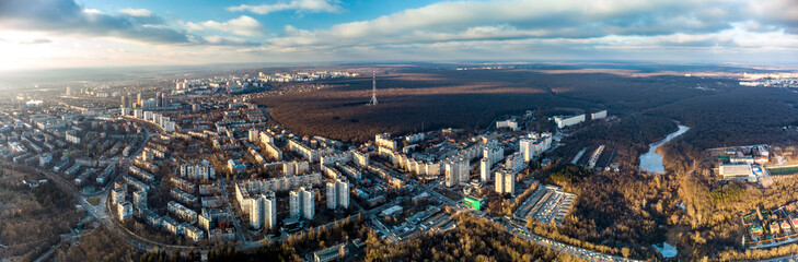 Fototapeta premium Aerial view Kharkiv city center and Pavlove Pole districts wide panorama. Multistorey buildings near forest with telecommunication tower antenna with scenic sky in winter