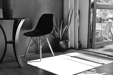 Black and white shot of a chair, a table and tree