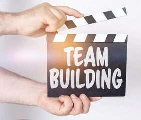 On a white background, a man holds a clapperboard in his hands on which it is written - TEAM...