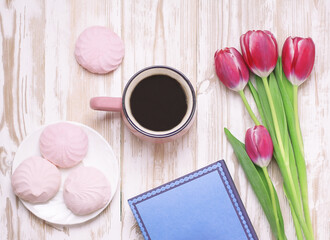 cup, flowers, book and marshmallows on the table