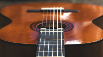 Fototapeta premium Wooden guitar on a wooden background, close-up, strings. Musical retro instrument. 