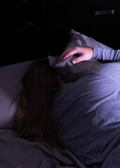 woman in bed hiding her face from the light