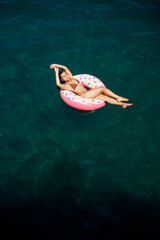 Young woman in a swimsuit swims on an inflatable ring in the sea. Summer vacation concept.