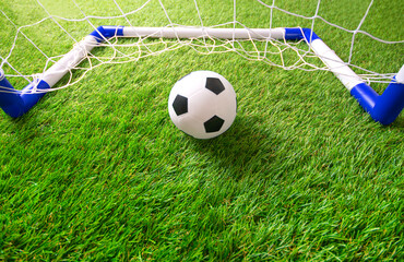 Children's mini football background with football goal and soccer ball on the soft artificial grass.