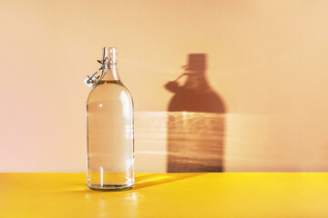 Glass bottle with clean drinking water lit by the sun. background with place for text