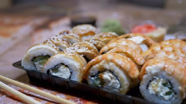 Japanese Sushi Rolls in Plastic Box are Served at Restaurant Table. 4K. Close-up
