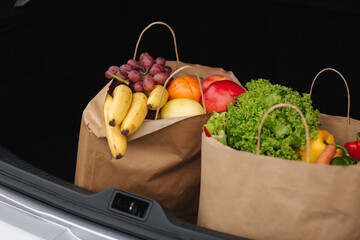 Groceries from a supermarket in a car trunk. Food delivery during quarantine. Cruft Paper eco bags for shopping. Fresh fruits and vegetables, vegan
