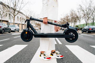 A woman carrying a folding electric scooter © OscarStock