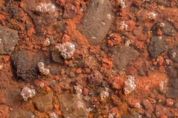 Rust colored background of rocks and water bubbles with orange and red.