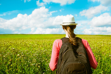 Naklejka na ściany i meble Female traveler looking out at a green field on a beautiful sunny day. 