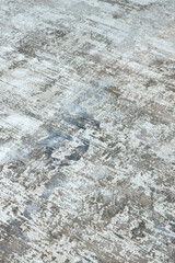 Background from a stylish carpet in neutral gray-beige-blue tones with fading and artificial antiquity effect. Concept details of a fashionable interior, carpets. Abstract texture. Vertical