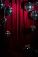design of a photo zone for guests - mirror disco balls against the background of a red velvet curtain.
