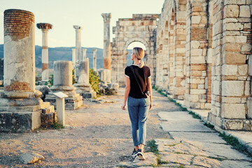 Happy young woman walking on ancient antique city Volubilis. Traveling by Morocco.