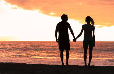 Man and woman on the beach walk and holding hands. People love and travel concepts. 