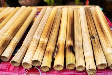 Street food market in Asia. A man sells rice in bamboo stalks