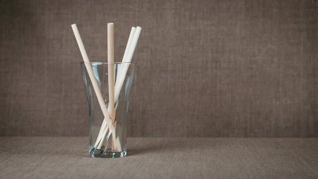 Fill a glass with straws. Somebody fill the glass with paper reusable straws in the room.