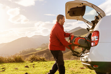 mountain person leaving his backpack in the trunk of his off-road car after a day of trekking. man...