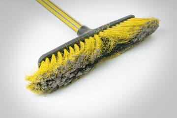 Yellow broom with a dusty pile.