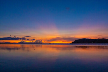 Wonderful sunset landscape on the seashore, colors of the sunset sky and silhouette of island in the water. incredible tropical sunset