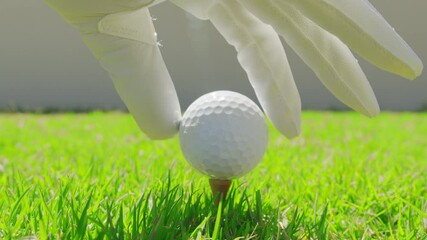 Golfer placing golf ball on the tee at golf course. Closeup.
