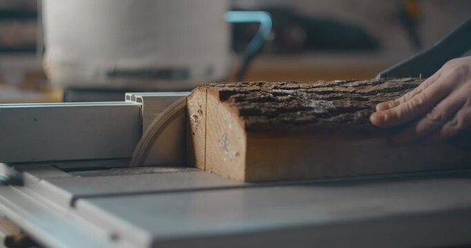 Carpenter saws logs on a circular saw in his workshop, making of the planks, slow motion carpentry, manufacture of products from timber, 4k DCI 60p Prores 422 HQ 10 bit