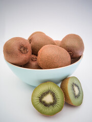 A light blue bowl with fresh kiwis on white background. Half of the kiwi.