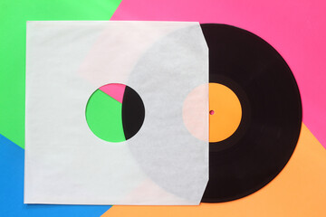 Aged white paper cover and black vinyl LP record isolated on colorful background