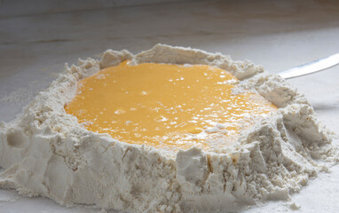 Homemade pasta, raw chicken eggs and flour  whipped on a white background.