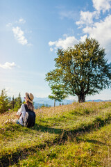 Traveling in summer Ukraine. Trip to Carpathian mountains. Happy woman tourist hiker sitting in flowers
