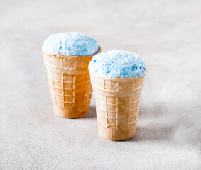 Blue ice cream with matcha tea, flax seeds in a waffle cup on a light gray background