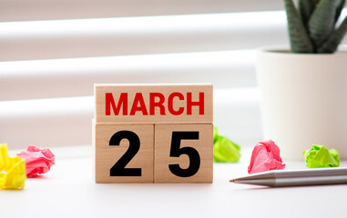 White block calendar present date 25 and month March on wood background