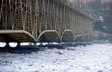 The ice floe presses against the steel bridge over the river