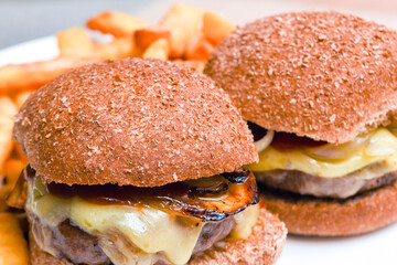 Cheese burger and fries with sauce on a white plate for a hot meal