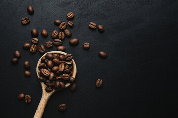 Coffee beans in spoon on dark