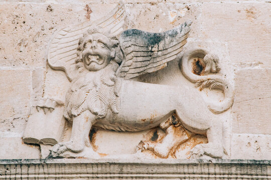 A bas-relief on the wall depicting a mythical lion with wings and a book in its paws.