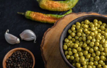 Marinated olives and pepper seeds over black background