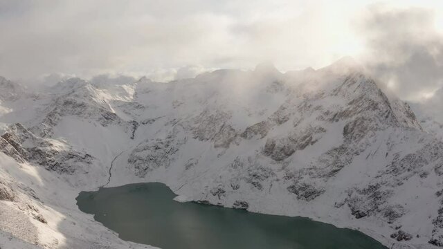 Heavenly Drone Shot of Snowy Mountain Summit and a Small Lake in the Middle