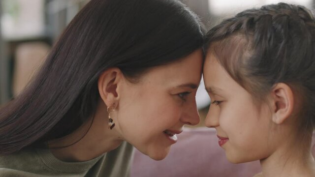Slowmo panning close up of loving mom and daughter looking at each other touching foreheads. Concept of love and motherhood