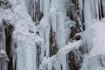 Closeup of thick layers of ice and icicles on rock in winter in Washington state
