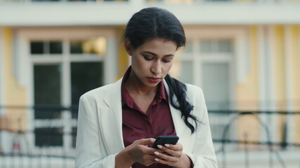Serious businesswoman texting message outdoors. Woman looking phone screen