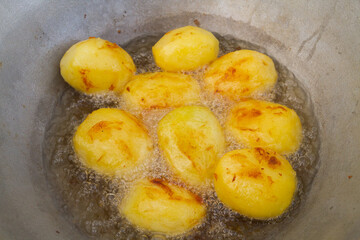 Golden potatoes are fried in boiling oil in a cauldron